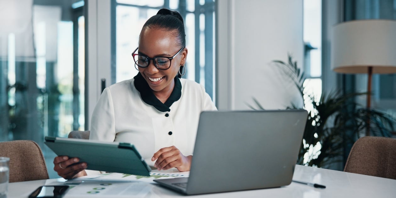 Businesswoman reviewing EDI mapping data on tablet and laptop in office