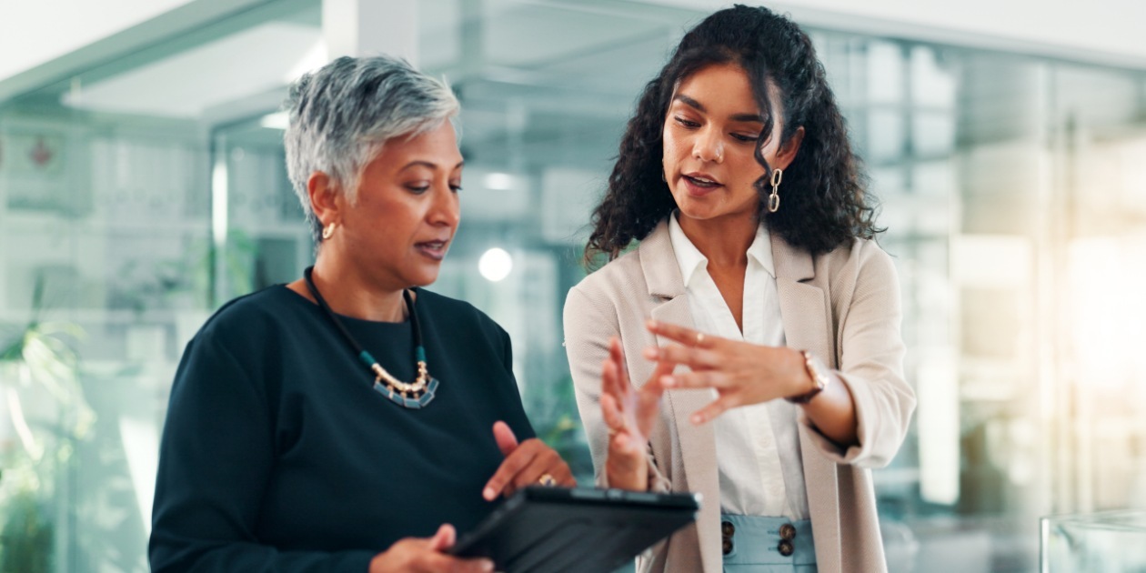 two-professional-women-discussing-work-on-tablet-in-modern-office