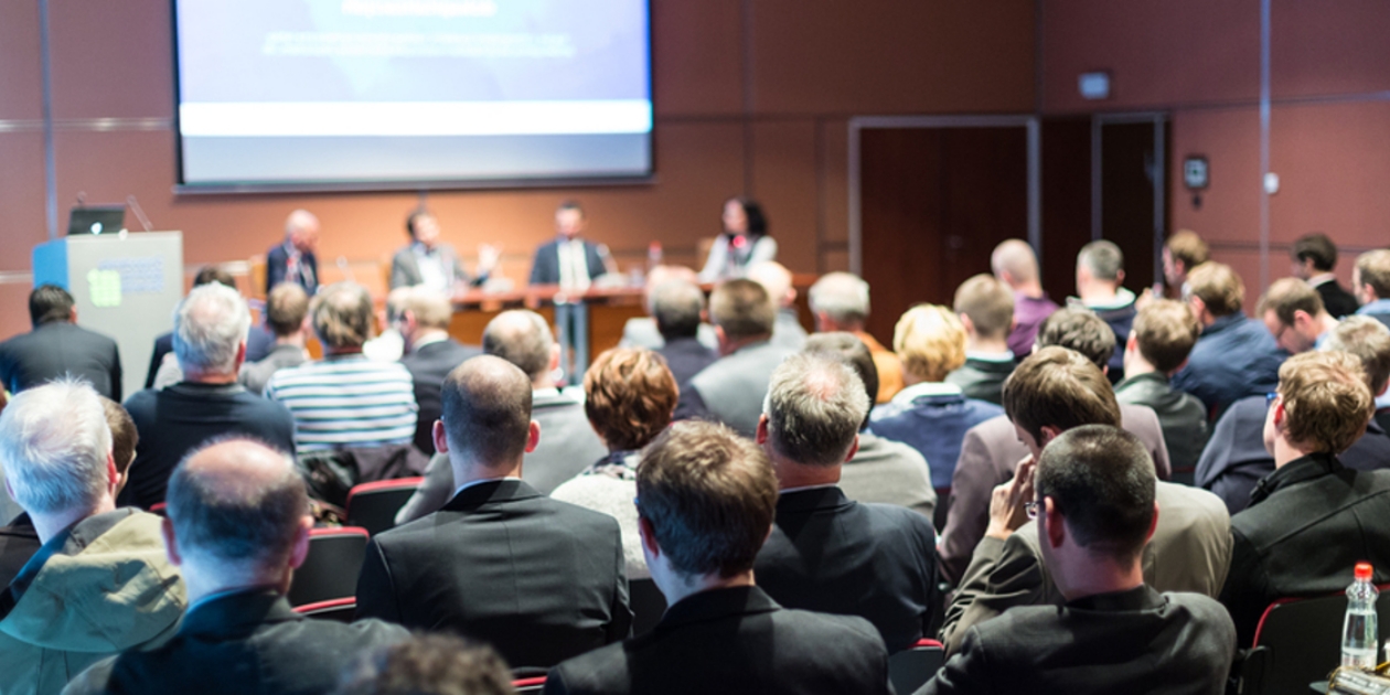 Conference room filled with participants and a panel.