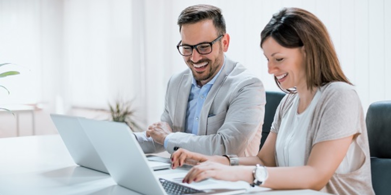 Smiling colleagues at their laptops