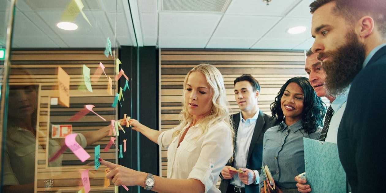 Team brainstorming EDI compliance best practices using sticky notes on a glass wall