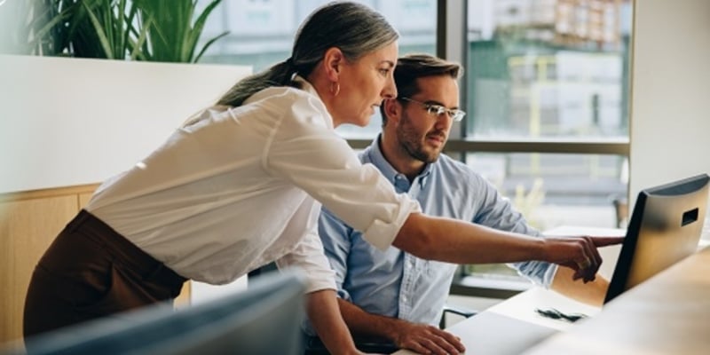 two colleagues looking at a desktop computer screen