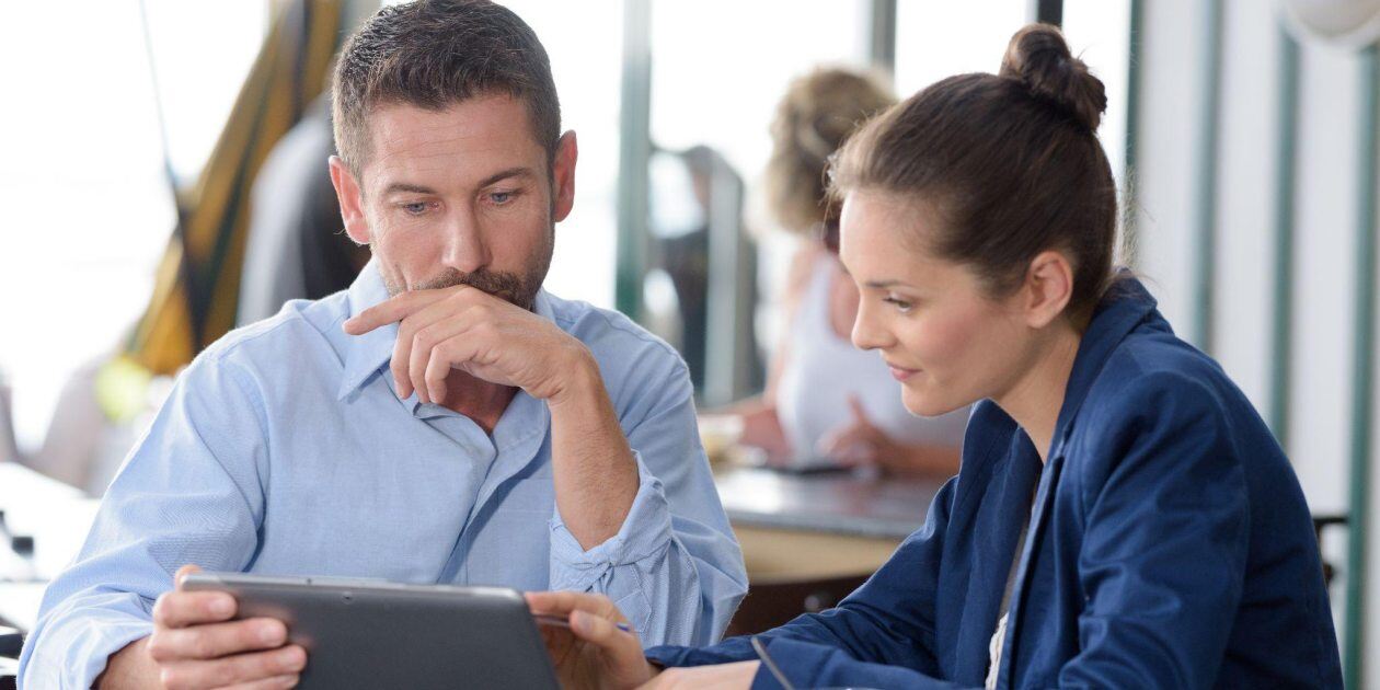 Man and woman discussing documents on a tablet in a modern office