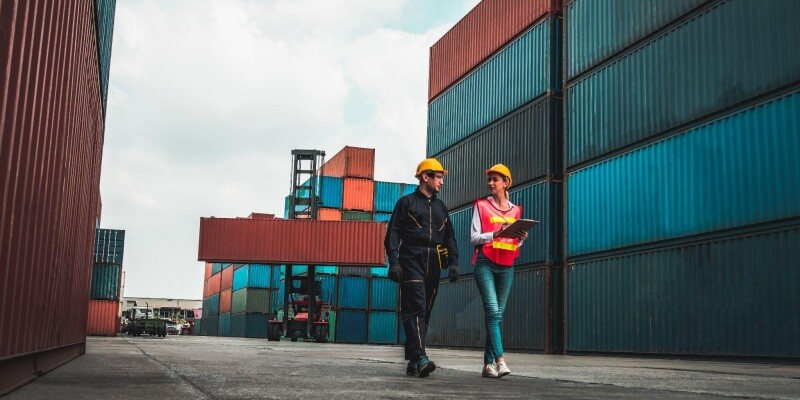 Workers discuss EDI automation in supply chain amid shipping containers