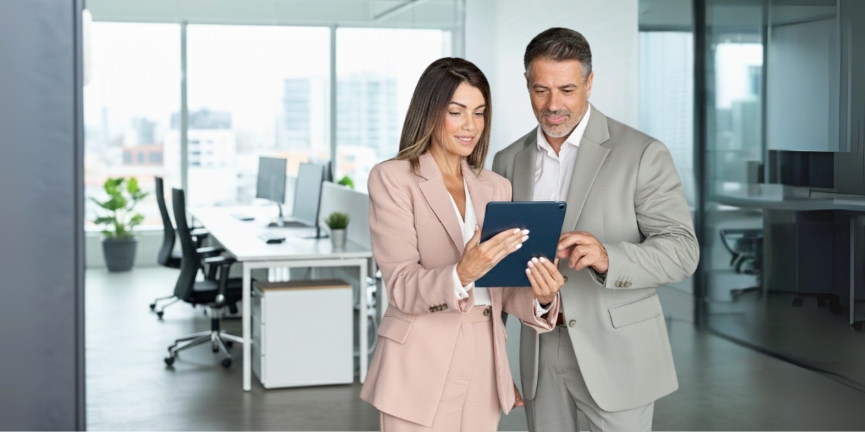 Business professionals in suits reviewing tablet in modern office with city view and plants
