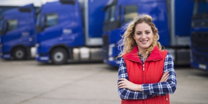 smiling woman stanStanding in front of transportation trucks
