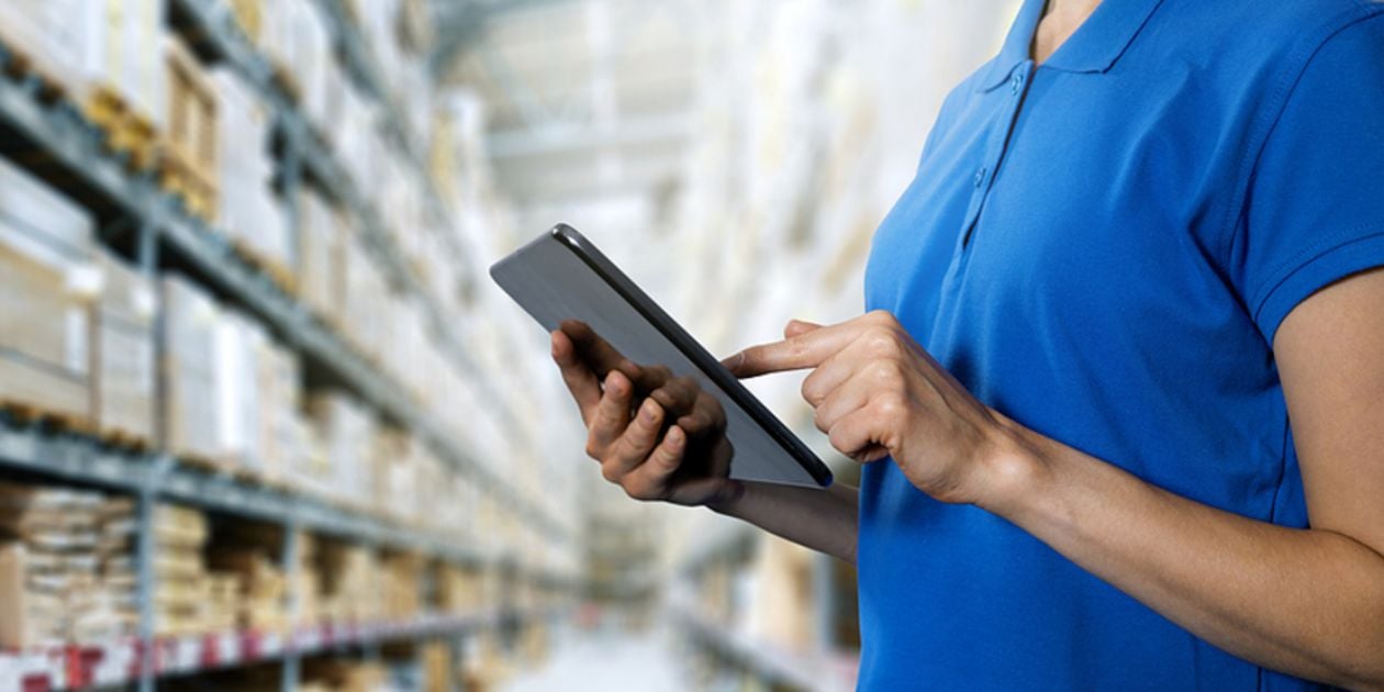 Typing on a tablet in a warehouse.