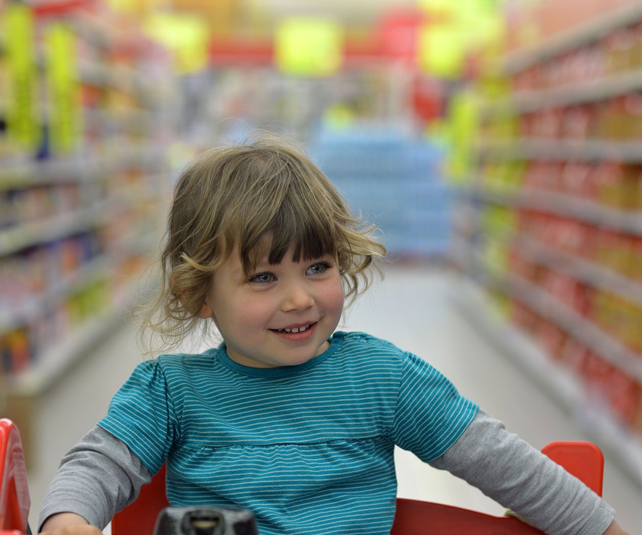A photo of a little girl in a shopping cart to illustrate environment where products from Remedi food and beverage clients are sold.